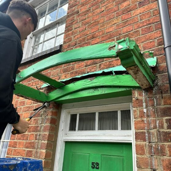 Person repairing overhang above green door