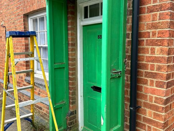 Green door with yellow ladder outside.