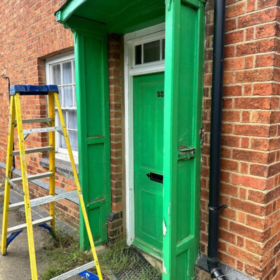 Green door with yellow ladder outside.