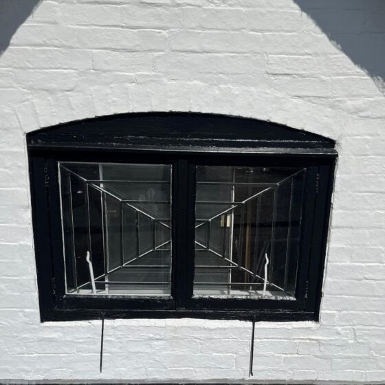 Black-framed small window on white brick wall.