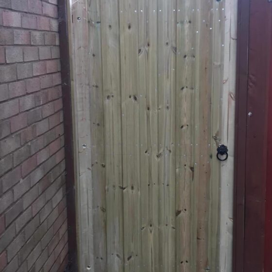 Wooden garden gate between brick walls.