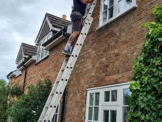 Man on ladder fixing house windows.