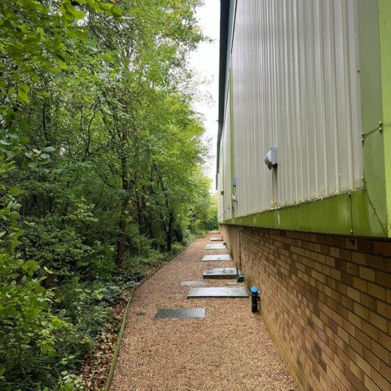 Path beside building and forest during daytime.